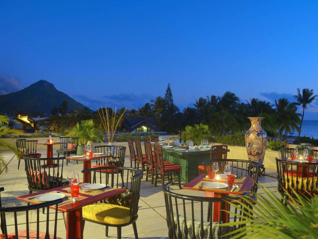 Romantiska terase ar skatu uz kalniem un jūru, kur galdi ir klāti ar elegantām maltītēm un dzērieniem. Apkārt ir tropu augi un mīksta apgaismojuma atmosfēra.