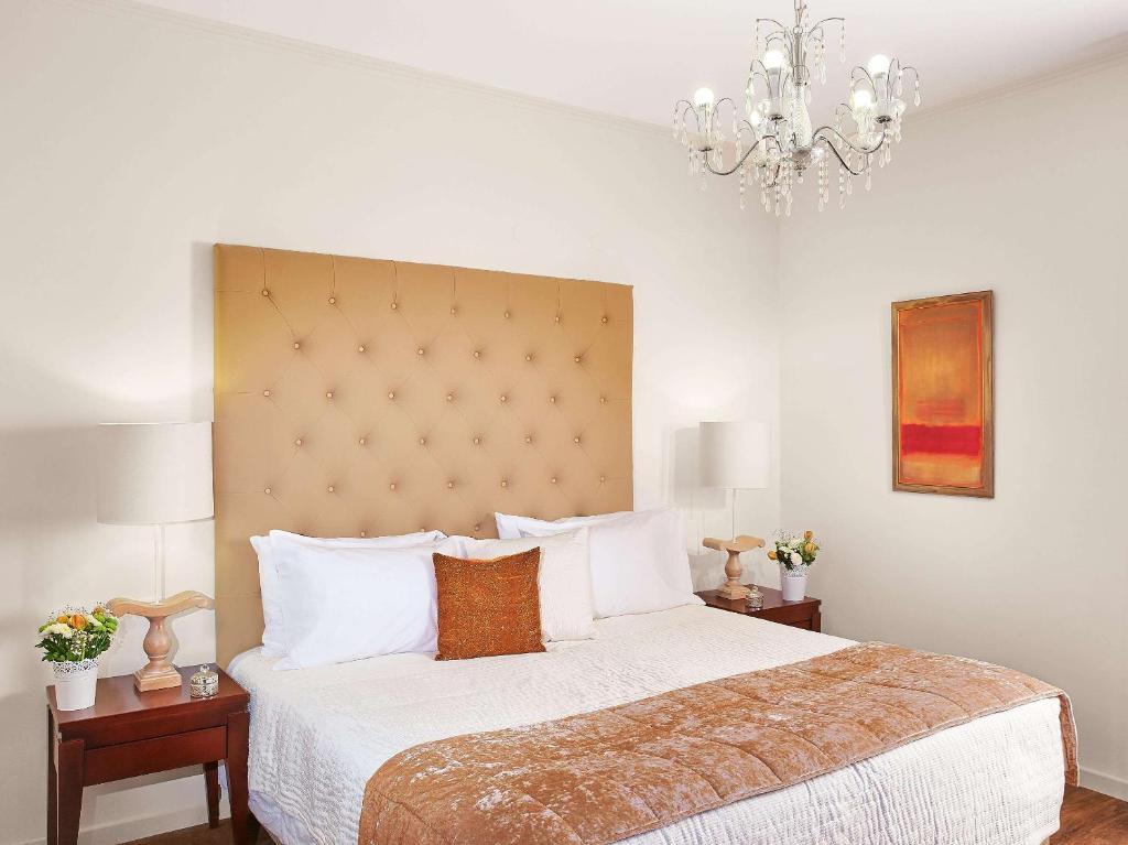 Elegants numurs viesnīcā Grecotel Casa Adele ar mīkstu gultu un modernu apgaismojumu.