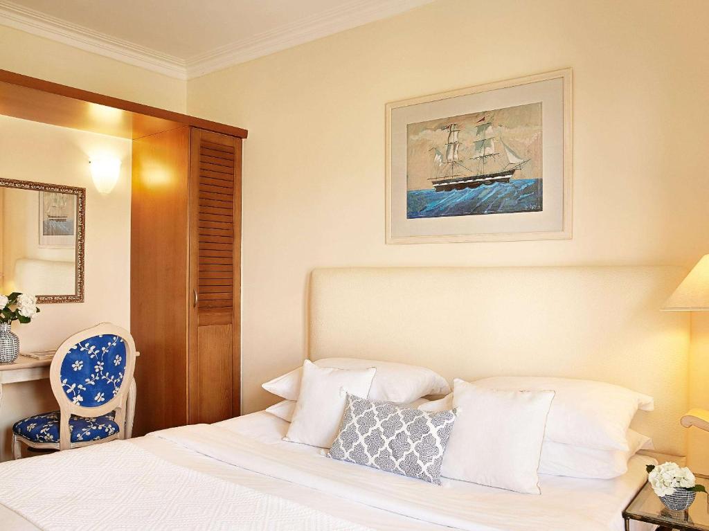 Grecotel Marine Palace & Aqua Park numurs ar gultu un mākslas darbu uz sienas.