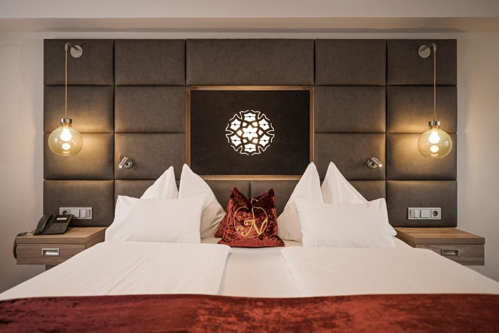 Mūsdienīgs guļamistabas interjers ar ērtu gultu, stilīgu apgaismojumu un dekoratīvām spilvenām. Sienas apdare un mēbeles rada siltu un viesmīlīgu atmosfēru.