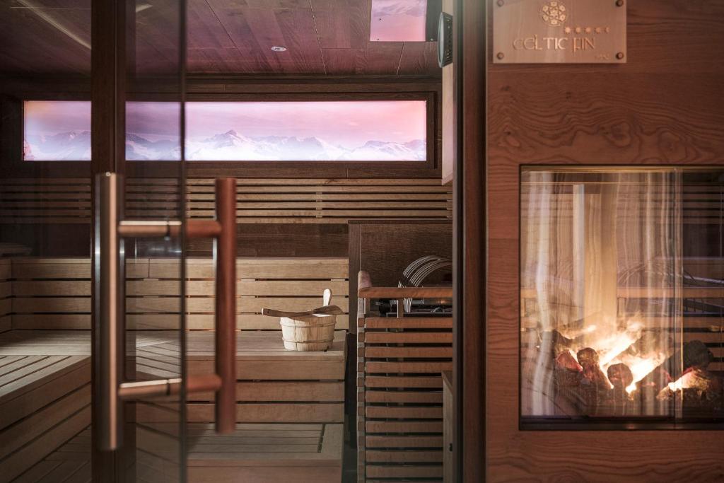 Mūsdienīga sauna ar koka interjeru, caur stiklu redzama uguns un kalnu ainava. Ideāla vieta relaksācijai un atpūtai.