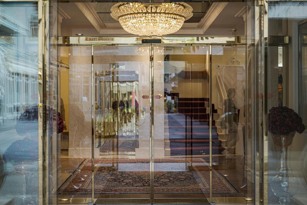 Luksusa ieeja ar stikla durvīm un greznu kristāla lustru, kas piesaista uzmanību. Interjers ir elegants, ar paklāju un dekoratīviem elementiem.