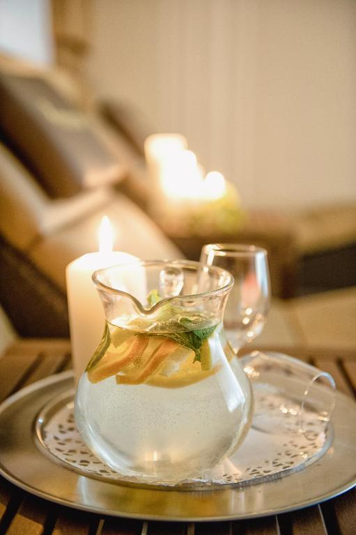 Auksta dzēriena karafe ar citrona un piparmētru šķēlītēm uz galda, blakus svecei un glāzēm. Ideāls brīdis relaksācijai un komfortam.