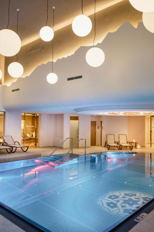 Mūsdienīgs spa ar baseinu, dekorētu ar stilīgām apaļām gaismām un elegantiem atpūtas krēsliem. Telpa izstaro relaksāciju un komfortu.