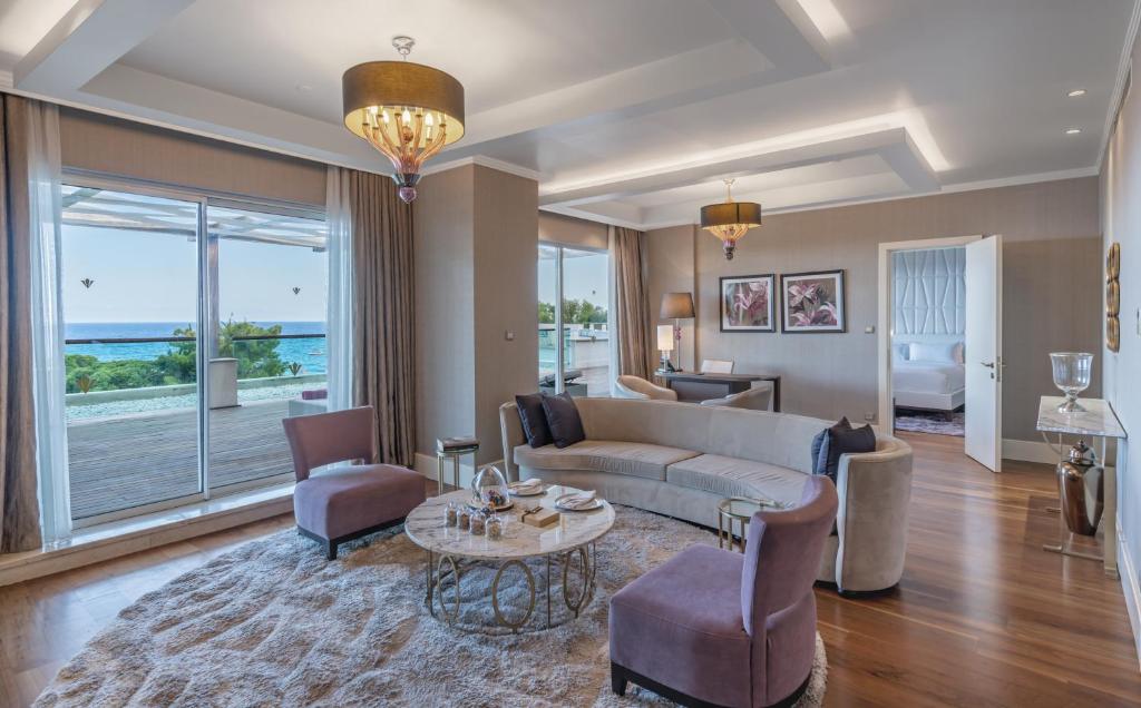 Eleganta viesnīcas Rixos Premium Tekirova numura dzīvojamā istaba ar skatu uz jūru.