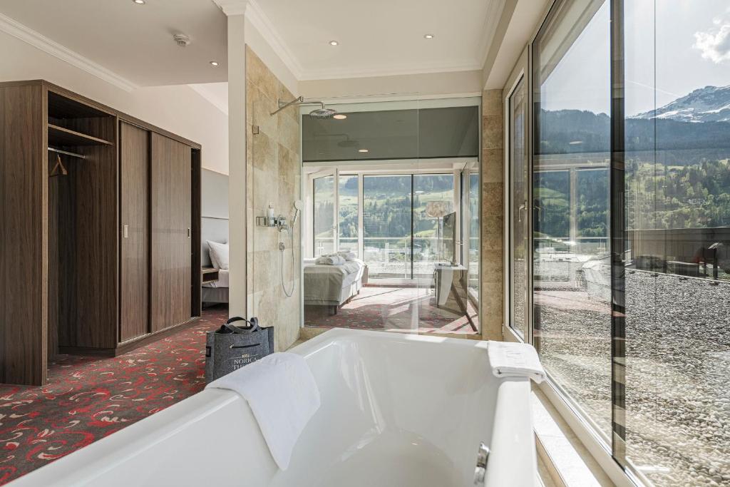 Mūsdienīgs viesnīcas numurs ar panorāmas logiem, vannu un skatu uz kalniem. Interjers apvieno eleganci un komfortu, radot relaksējošu atmosfēru.