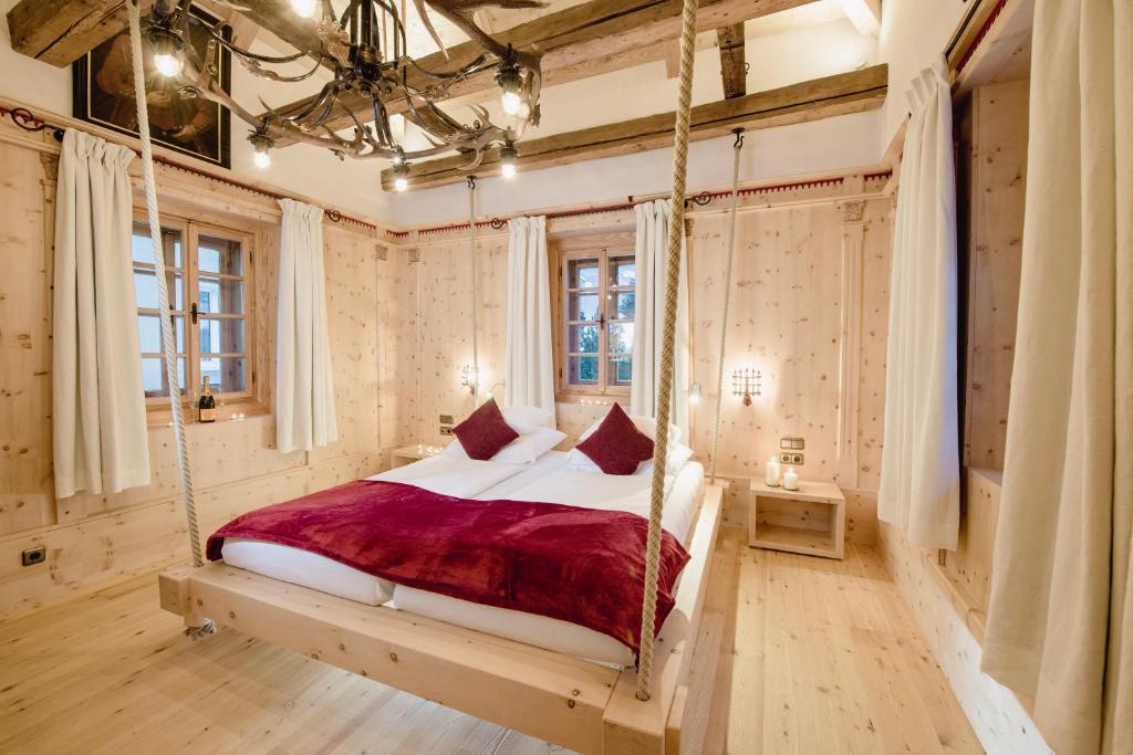 Mūsdienīga guļamistaba ar koka elementiem, šūpojošu gultu un siltu apgaismojumu. Interjers izceļas ar gaišām krāsām un dabīgām koka virsmām.