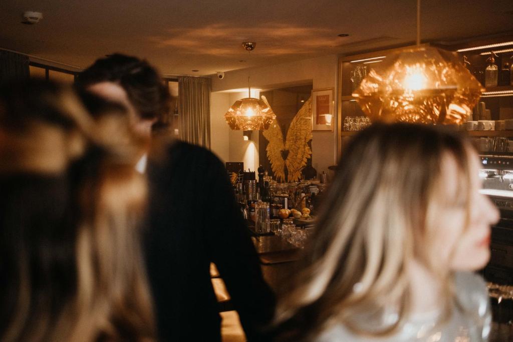 Kafejnīcas iekšskats ar mirdzošām lampām un elegantām interjera detaļām. Fons ir izplūdis, radot noslēpumainu atmosfēru.