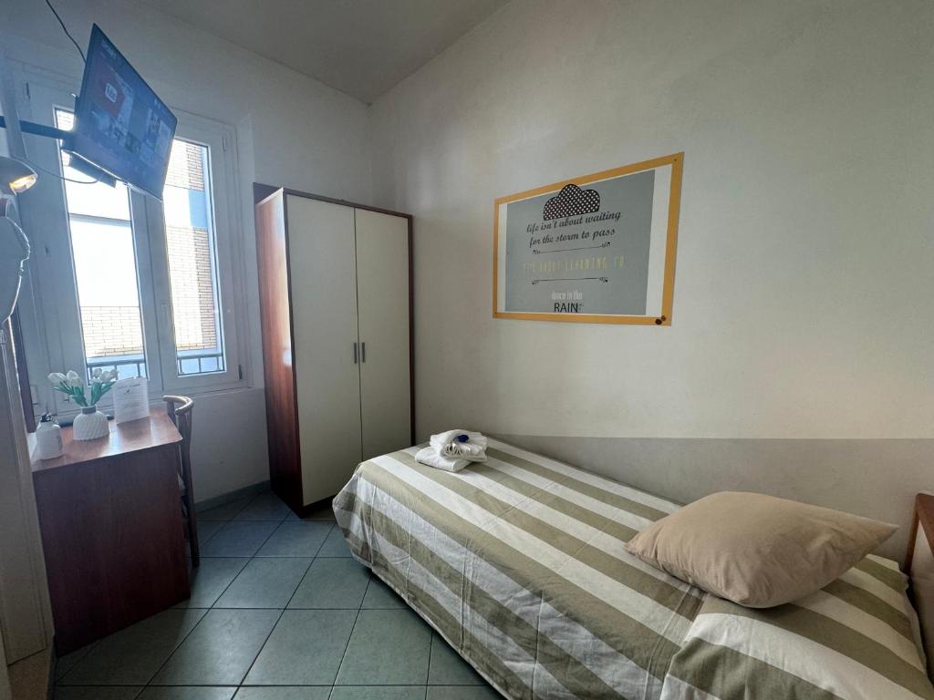 Maza, gaiša istaba ar vienguļamo gultu, rakstāmgaldu un televizoru pie loga. Uz sienas redzama motivējoša plakāts.