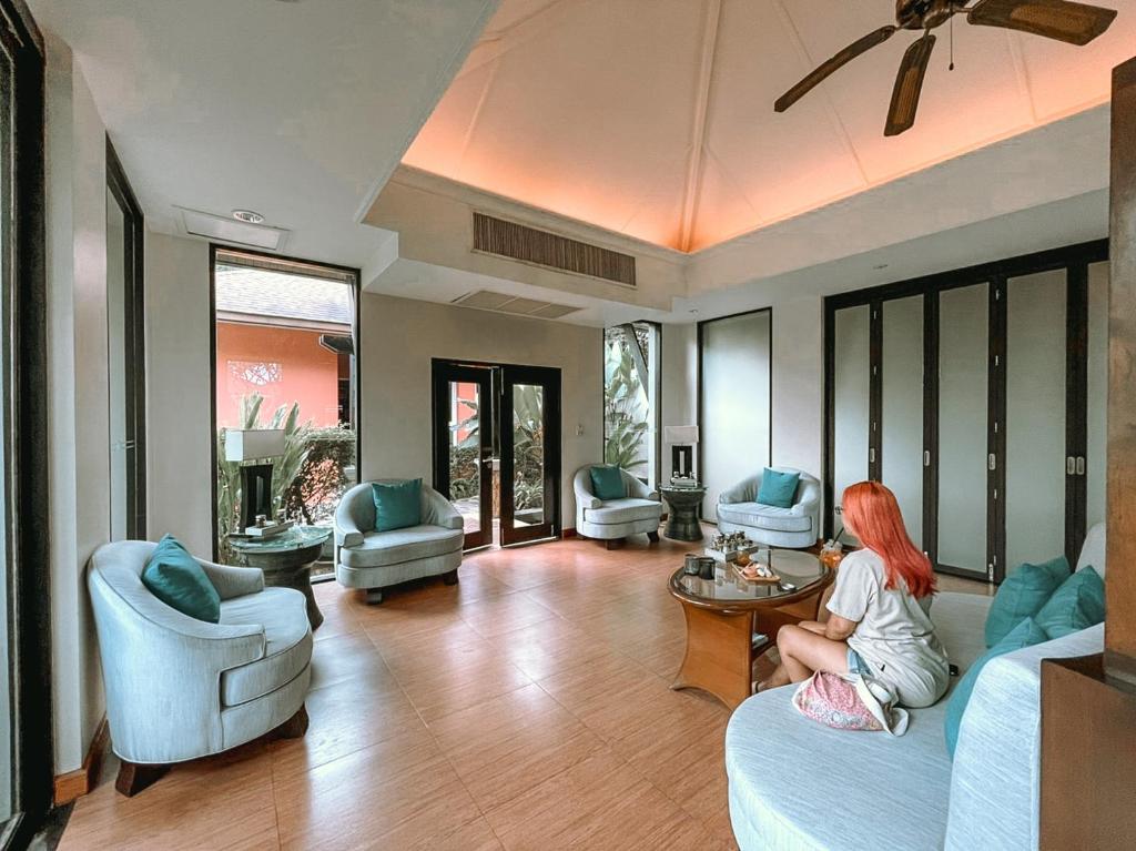 Mūsdienīgs un gaišs atpūtas telpa ar komfortablām krēslām un galdu, kurā var redzēt cilvēku, kas bauda uzkodas. Telpā ir lieli logi ar skatu uz dabu.