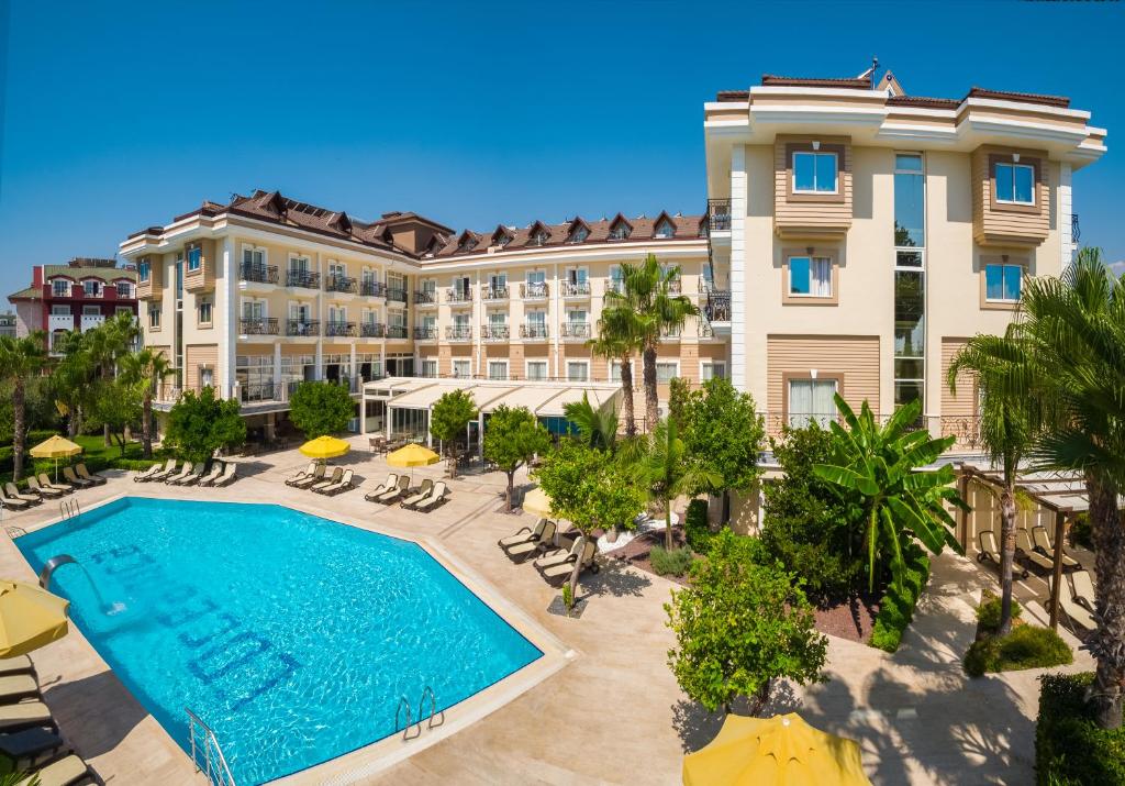 L'oceanica Beach Resort Hotel baseins ar palmām un sauļošanās krēsliem piekrastē.