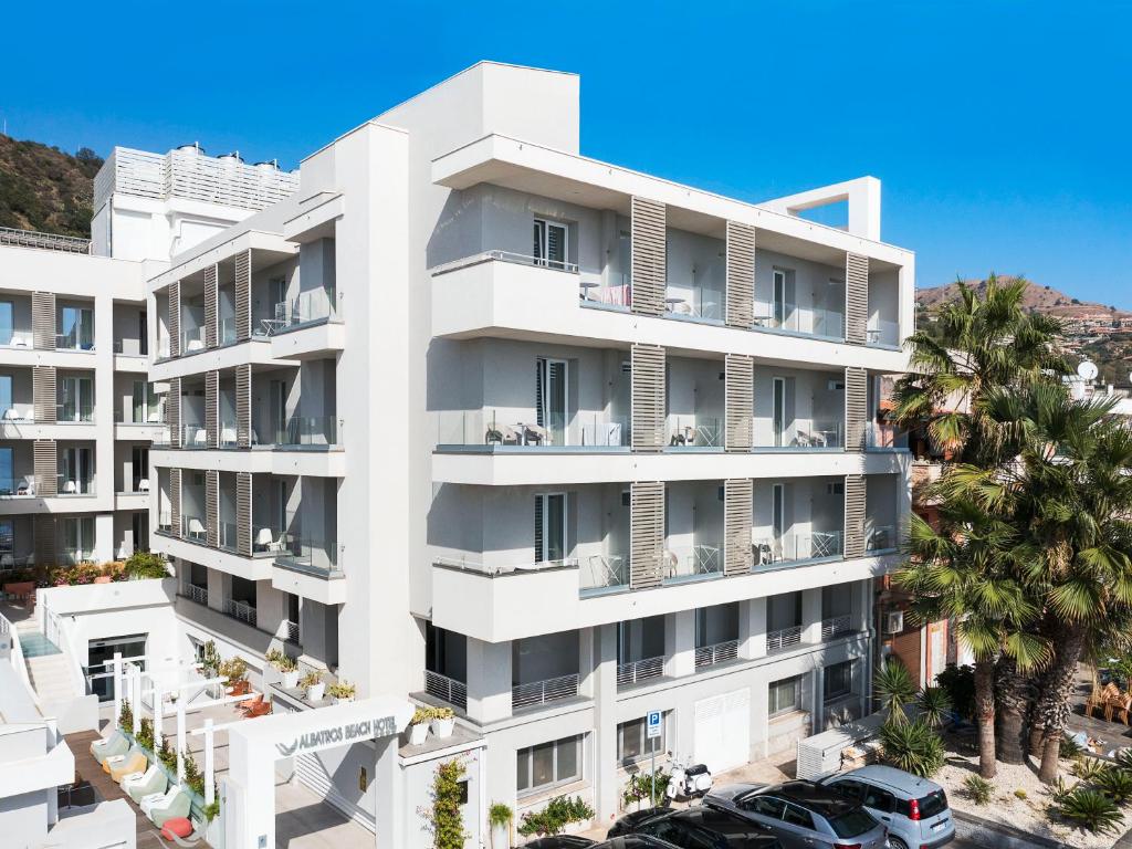 Mūsdienīga viesnīca ar balkoniem, kas piedāvā sauli un komfortu, atrodas pie pludmales. Apkārt viesnīcai ir zaļumi un automašīnas stāvvieta.