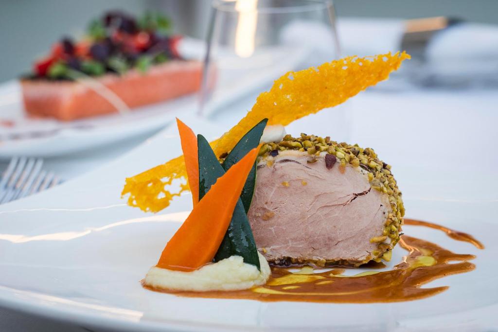 Gurķu un burkānu garnējums ar riekstu apvalkā ceptu gaļu, pasniegts ar krēmīgu mērci. Elegantais restorāna ēdiens ar krāsainām dārzeņu dekorācijām.