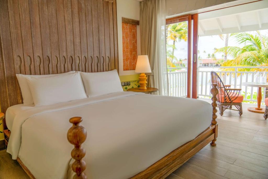 Mūsdienīgs viesnīcas numurs ar plašu gultu, koka mēbelēm un skatu uz dārzu. Interjers ir gaišs un komfortabls, radot relaksējošu atmosfēru.