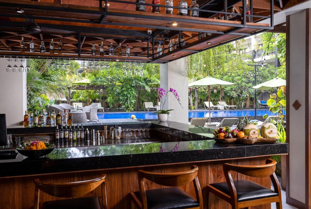Bārs pie Taksu Hotel Sanur ar skatu uz baseinu un tropisko dārzu.