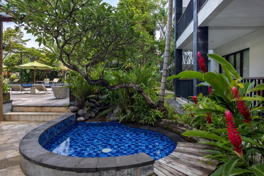 Taksu Hotel Sanur baseins ar zilu flīžu un tropisko augļu dārzu.