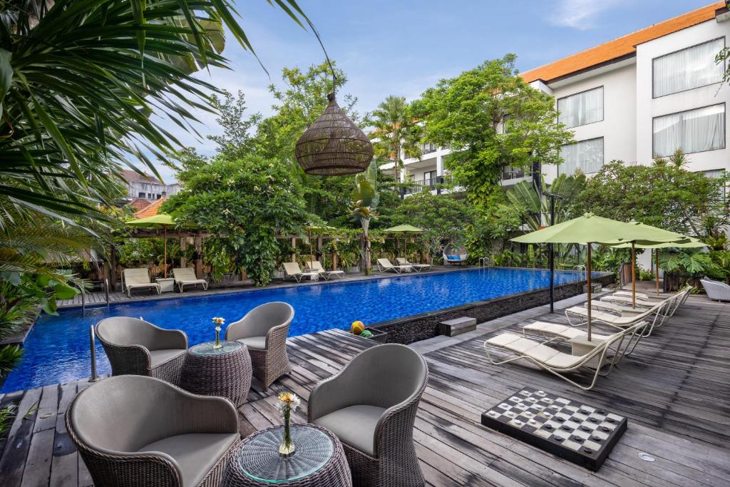 Taksu Hotel Sanur baseins ar zaļo ainavu un atpūtas zonu