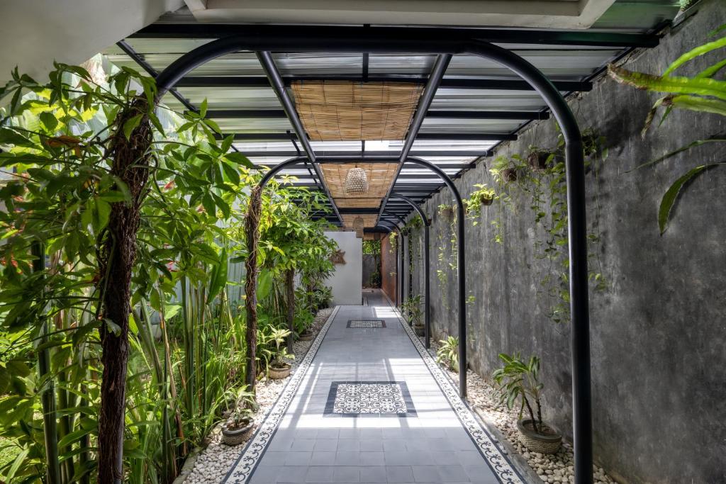 Taksu Hotel Sanur zaļš ceļš ar augiem un modernu arhitektūru.