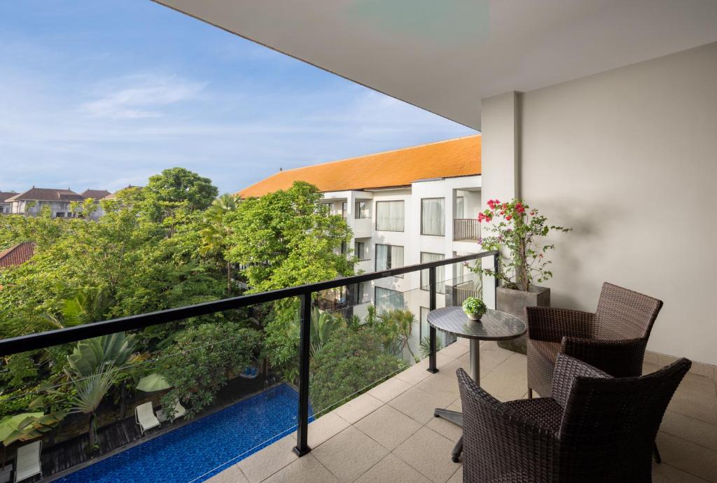 Taksu Hotel Sanur balkons ar skatu uz zaļo dārzu un baseinu.