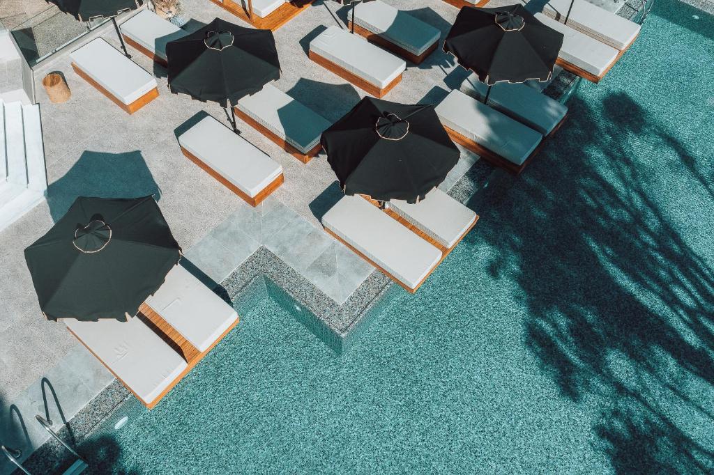 Baseina zona ar sauļošanās krēsliem un melniem saulessargiem, kas atrodas pie ūdens. Mūsdienīgs dizains un relaksējoša atmosfēra.