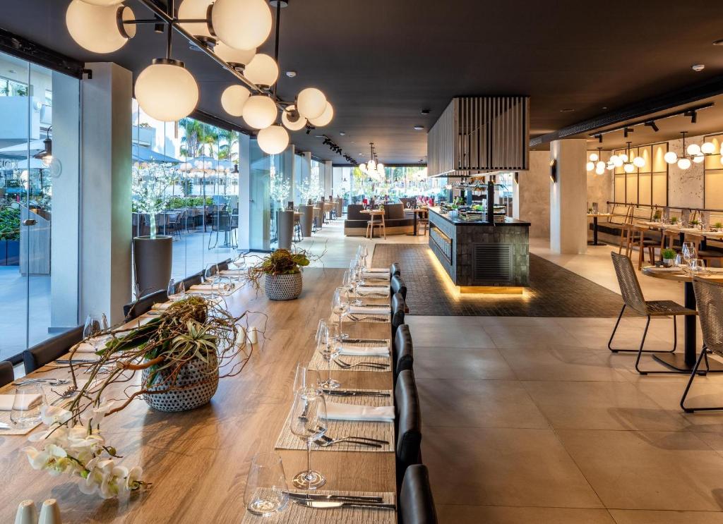 Mūsdienīgs restorāns ar elegantu interjeru, plašām telpām un apgaismojumu no apaļām lampām. Galdi ir skaisti klāti, radot aicinošu atmosfēru.