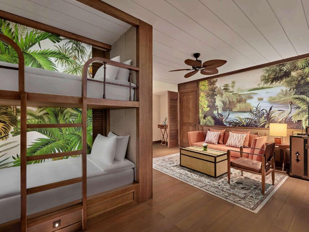 Mūsdienīgs viesnīcas numurs ar bunkuru tipa gultām, dekorēts ar tropu motīviem un gleznainu ainavu uz sienas. Telpā ir komfortabla atpūtas zona ar dīvānu un galdu.