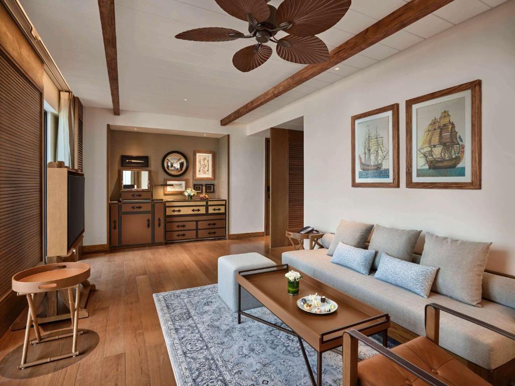 Mūsdienīgs viesistabas interjers ar koka grīdu, komfortablu dīvānu un gleznu ar kuģiem uz sienas. Telpā ir arī dekoratīvi elementi un gaismas avoti, kas radījuši siltu atmosfēru.