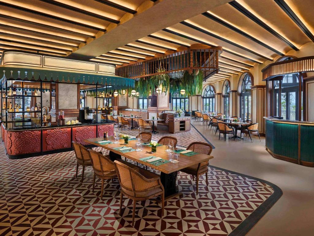 Elegants restorāns ar modernu interjeru, kas piedāvā maigas krāsas un stilīgas mēbeles. Gaismas un zaļumi rada patīkamu atmosfēru, ideālu maltīšu baudīšanai.