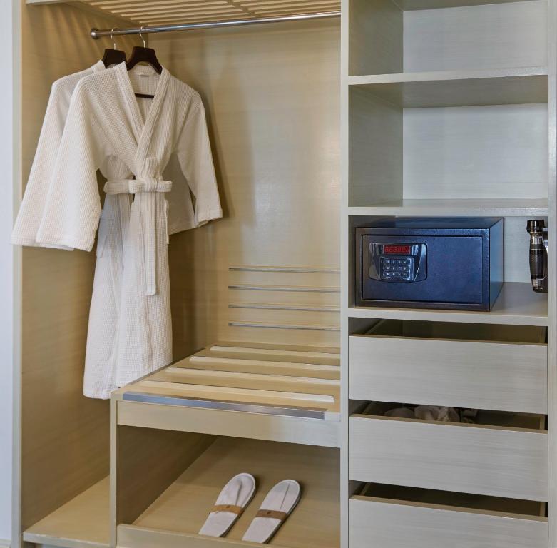 Mūsdienīgs garderobes skapis ar baltu halātu, čībām un seifu, ideāls viesnīcas numuram. Eleganta un funkcionāla uzglabāšana.