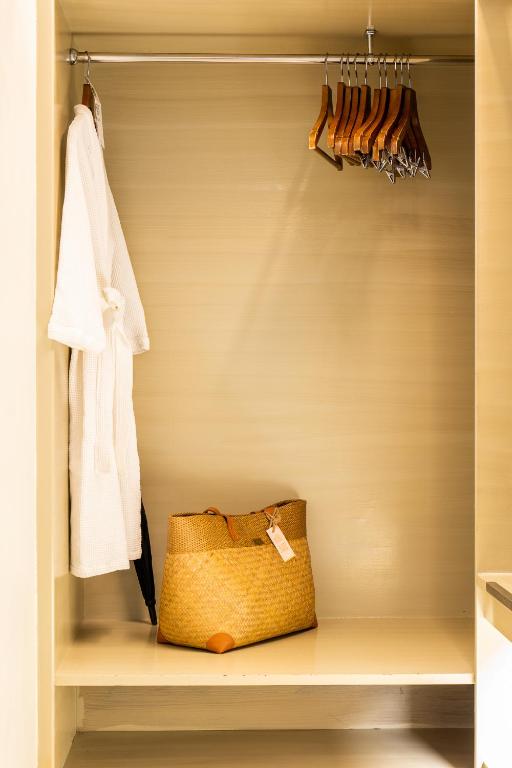 Tukšs skapis ar koka pakarami un peldmēteļa, kā arī zeltainu somu uz plaukta.