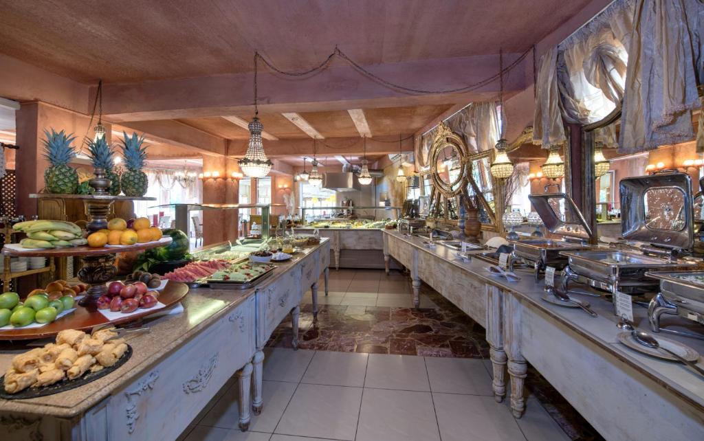 Bagātīgs bufetes galds ar svaigiem augļiem un gardumiem, apgaismots ar elegantiem lampām un dekoratīviem elementiem. Ideāla vieta brokastu baudīšanai.