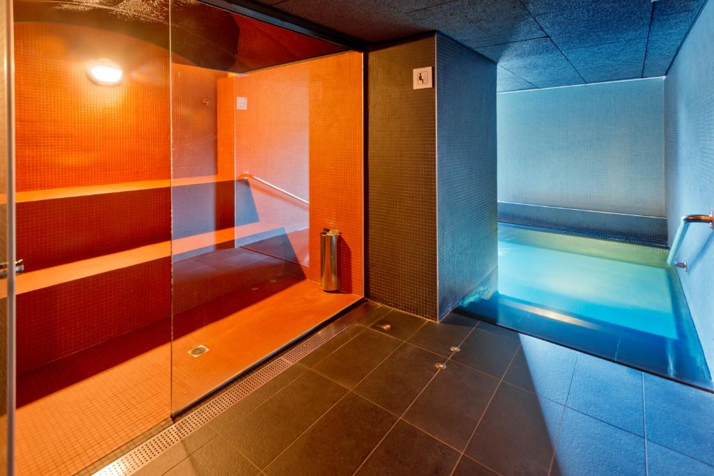 Mūsdienīgs saunas un peldbaseina interjers ar siltām krāsām un elegantu dizainu, kas rada relaksējošu atmosfēru.