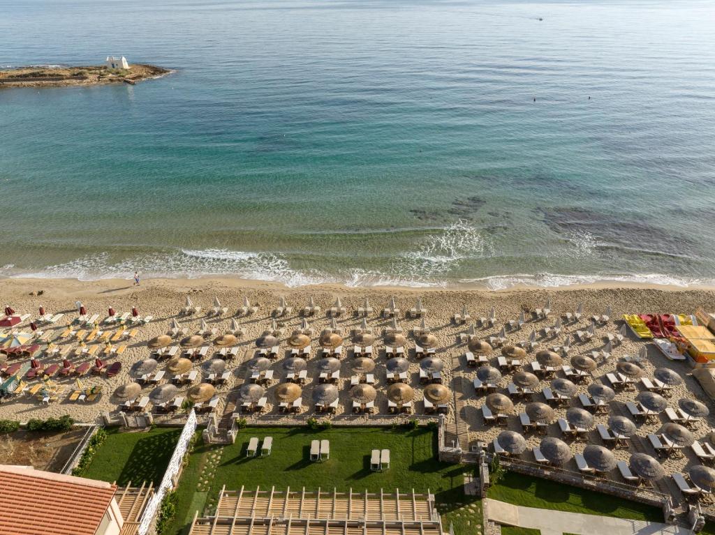 Pludmales skats ar saulessargiem un sauļošanās krēsliem, mierīga jūra un smilšaina piekrastes līnija. Ideāla vieta atpūtai un relaksācijai.