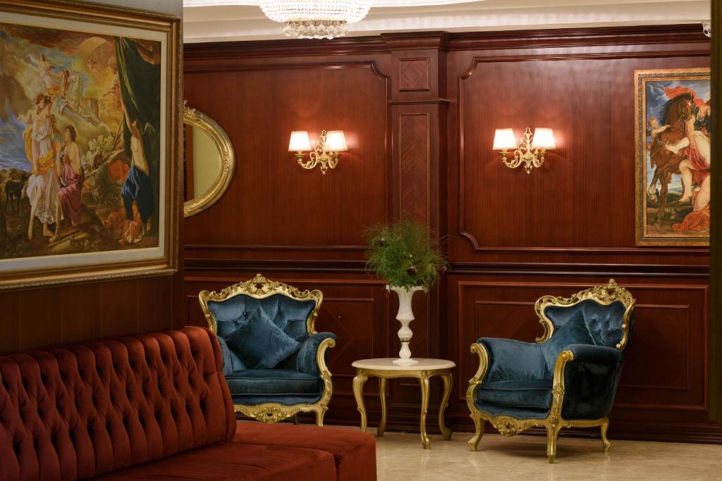 Eleganta atpūtas zona viesnīcā Antique Roman Palace ar zilu krēslu un mākslas darbiem.