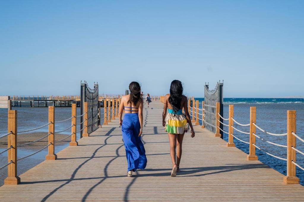 Divas personas staigā pa koka molu Sunrise Garden Beach Resort piekrastē.