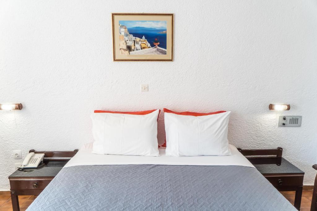 Mūsdienīgs viesnīcas numurs ar divām spilveniem un gultu, dekorēts ar gleznainu ainavu, kas piešķir mājīgu atmosfēru. Gultas blakus atrodas telefons un naktsgaldiņš.