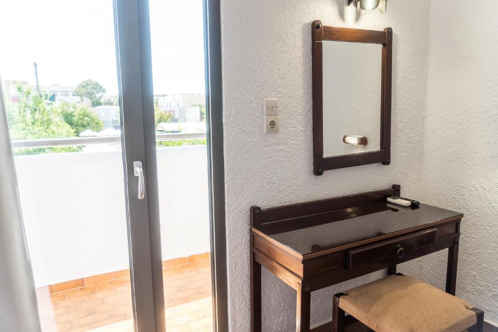 Koka tualetes galdiņš ar spoguli, blakus atvērtām durvīm uz balkonu, kas sniedz gaišu un svaigu gaisotni.