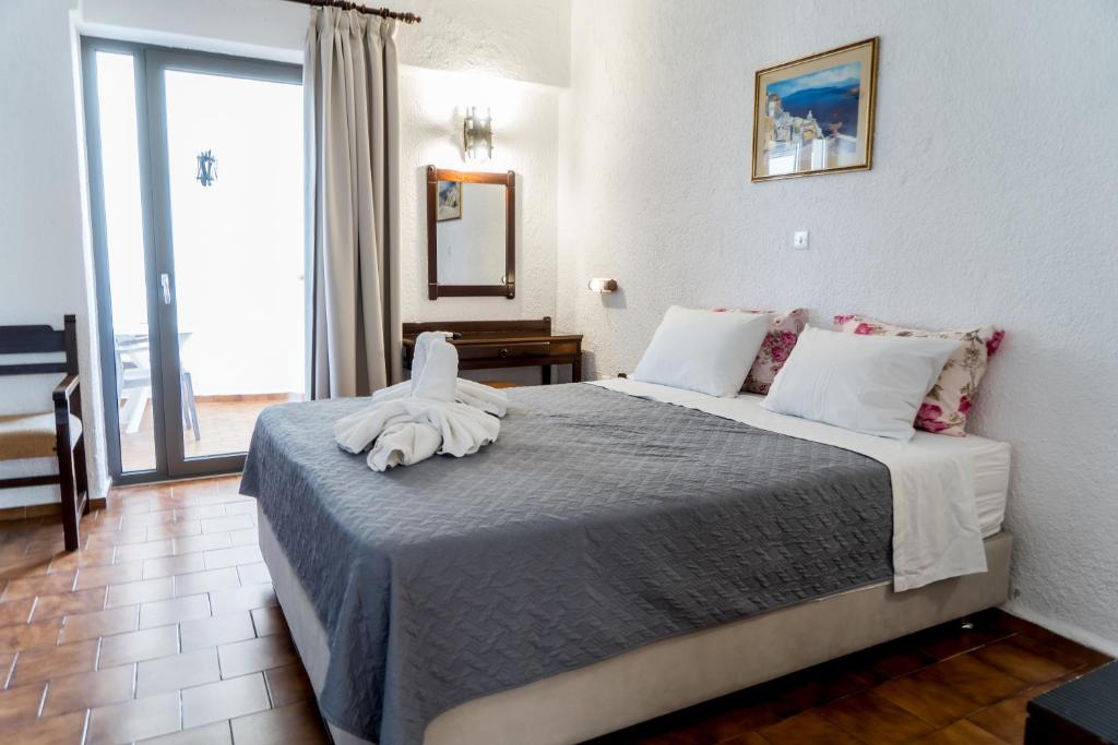 Mūsdienīga viesnīcas numuriņa iekārtojums ar divguļamo gultu, mīkstiem spilveniem un balkonu. Telpa ir gaiša un viesmīlīga, ar elegantu dizainu un mākslas darbu uz sienas.