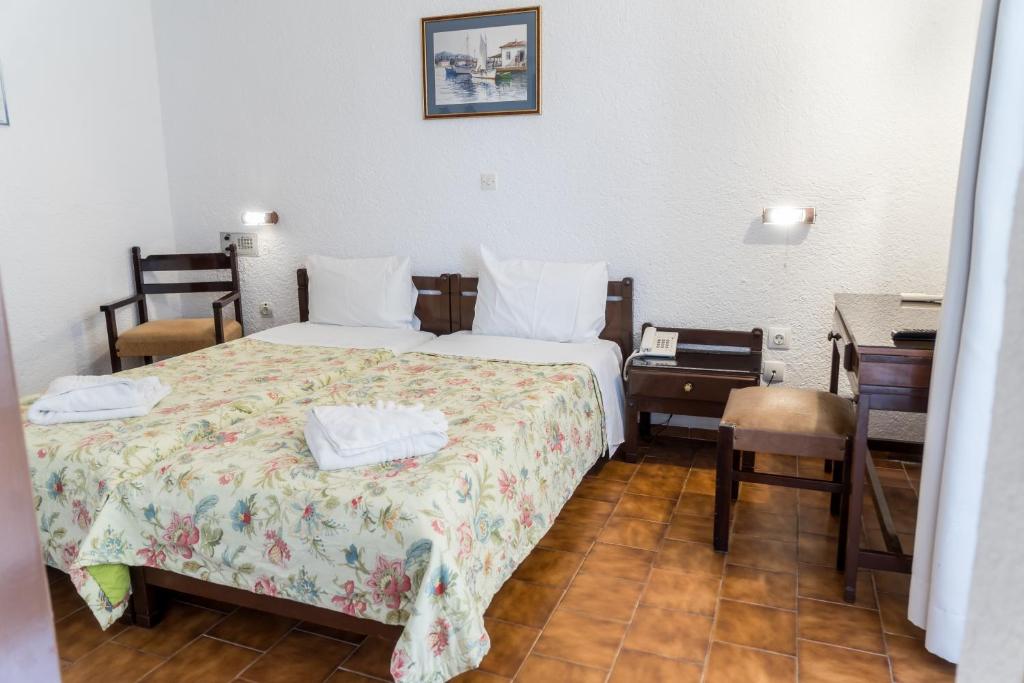 Gultas numurs ar divām gultām, koka mēbelēm un zemu galdu, ar ziedu raksta gultas veļu un baltiem dvieļiem. Sienas ir baltas, un telpā ir dabiska gaisma.