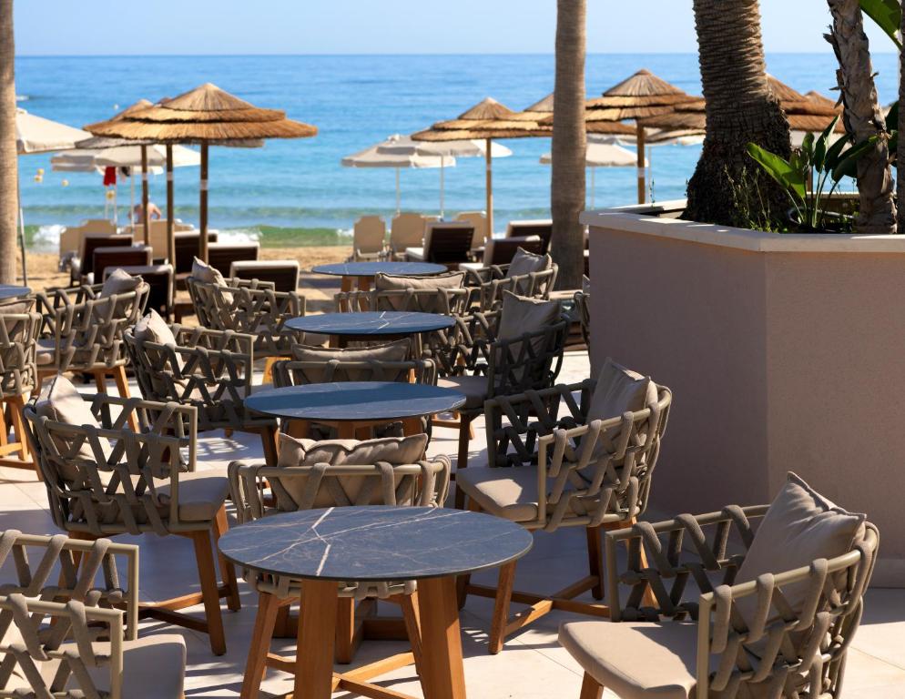 Pludmales kafejnīca ar modernām krēslām un galdiem, kas piedāvā skatu uz jūru. Viegla atmosfēra un relaksējoša vide brīvdienu baudīšanai.