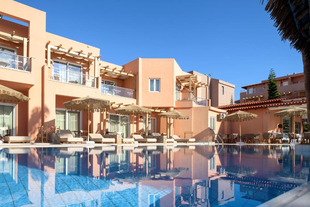 Viesnīcas komplekss blakus baseinam ar saulessargiem un atpūtas krēsliem, siltā saulē un skaidrā debesīs. Ideāla vieta relaksācijai un atpūtai.