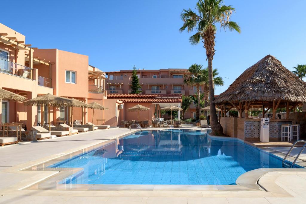 Peldbaseins ar saules gultām un palmu ainavu, apkārtne veidota ar modernām ēkām un tradicionālu salmu jumtu. Ideāla vieta atpūtai un relaksācijai.