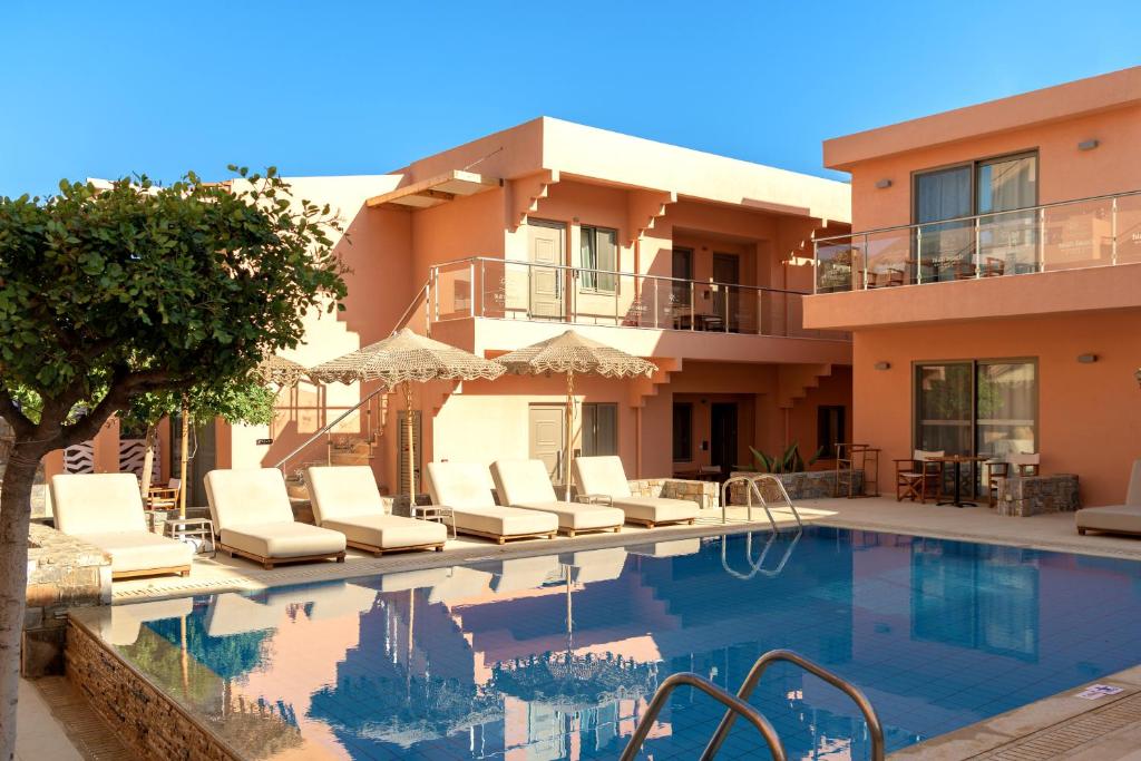 Viesnīcas komplekss ar peldbaseinu un sauļošanās krēsliem, apkārt augoša koku zaļums un saulaina debess. Ideāla vieta atpūtai un relaksācijai.