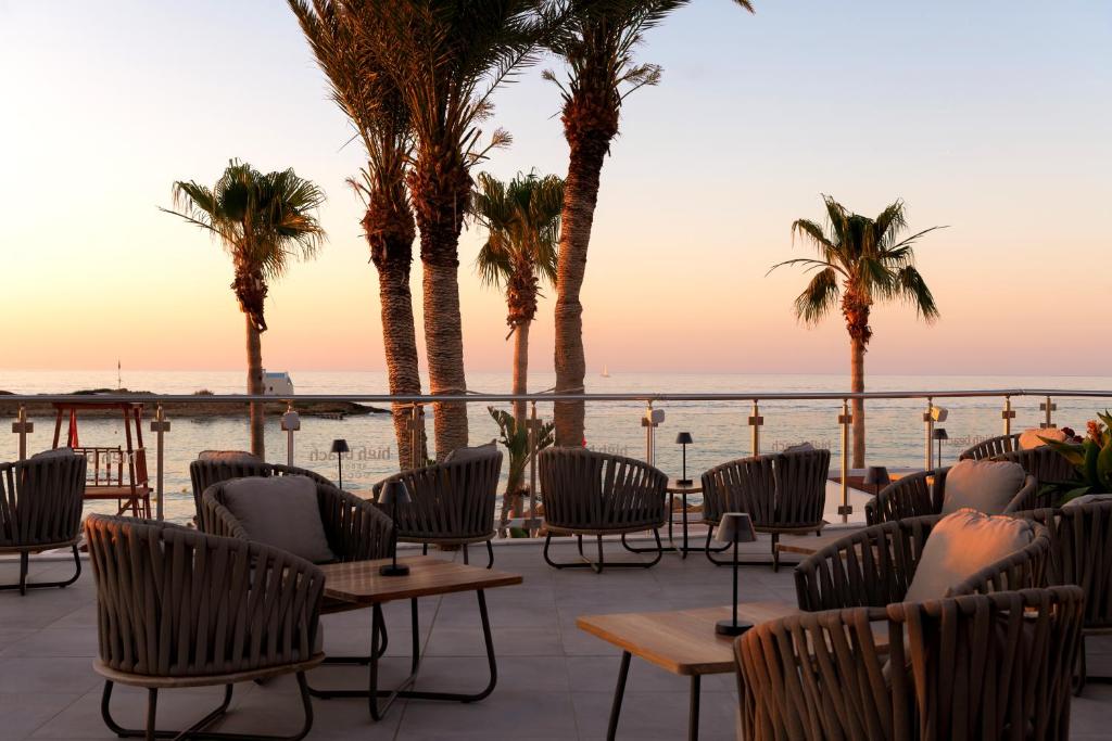 Terases skats uz jūru ar palmām un komfortablām sēdvietām, saulrieta gaismā. Ideāla vieta relaksācijai un baudīšanai.