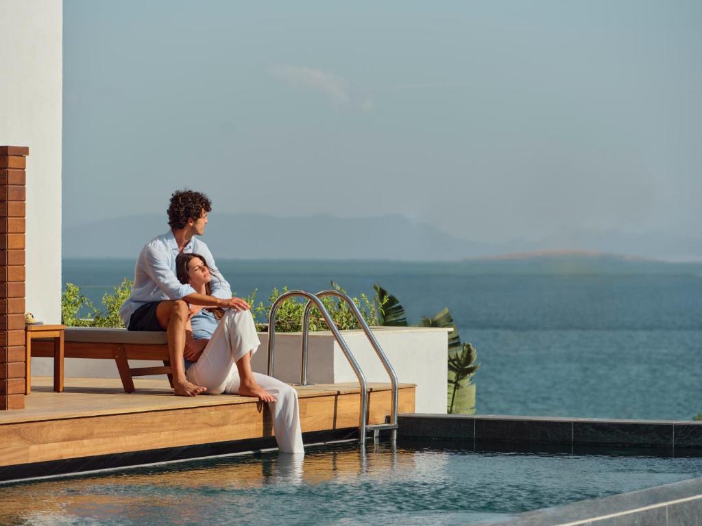 Pāris atpūšas pie baseina Anda Barut Collection, ar skatu uz jūru.