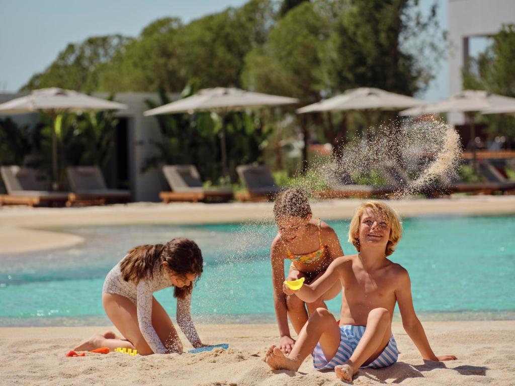 Bērni rotaļājas pludmalē pie Anda Barut Collection, priecājoties par sauli.