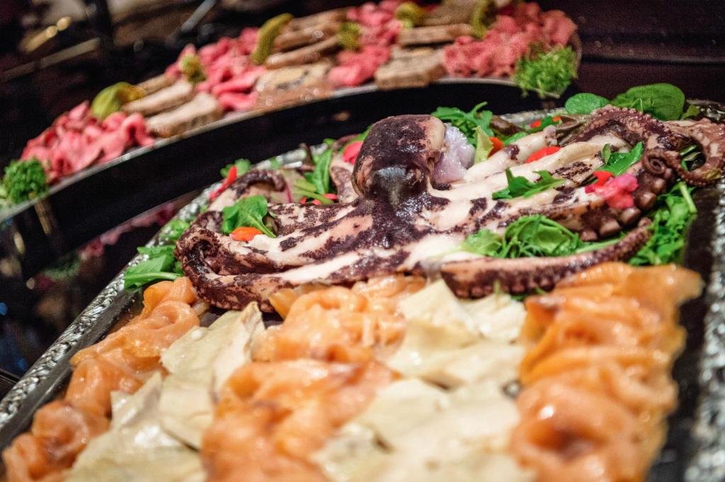 Svaigu jūras velšu platter ar astoņkāju un dažādiem zivs un gaļas izstrādājumiem, grezns pasniegšanas veids ar zaļumiem.