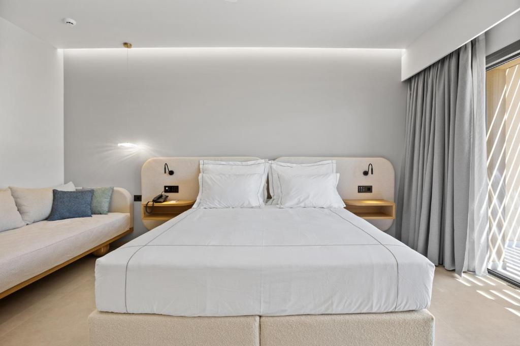 Mūsdienīgs viesnīcas numurs ar gultu, dīvānu un elegantiem apgaismojuma risinājumiem. Interjers ir gaišs un minimalistisks, radot relaksējošu atmosfēru.