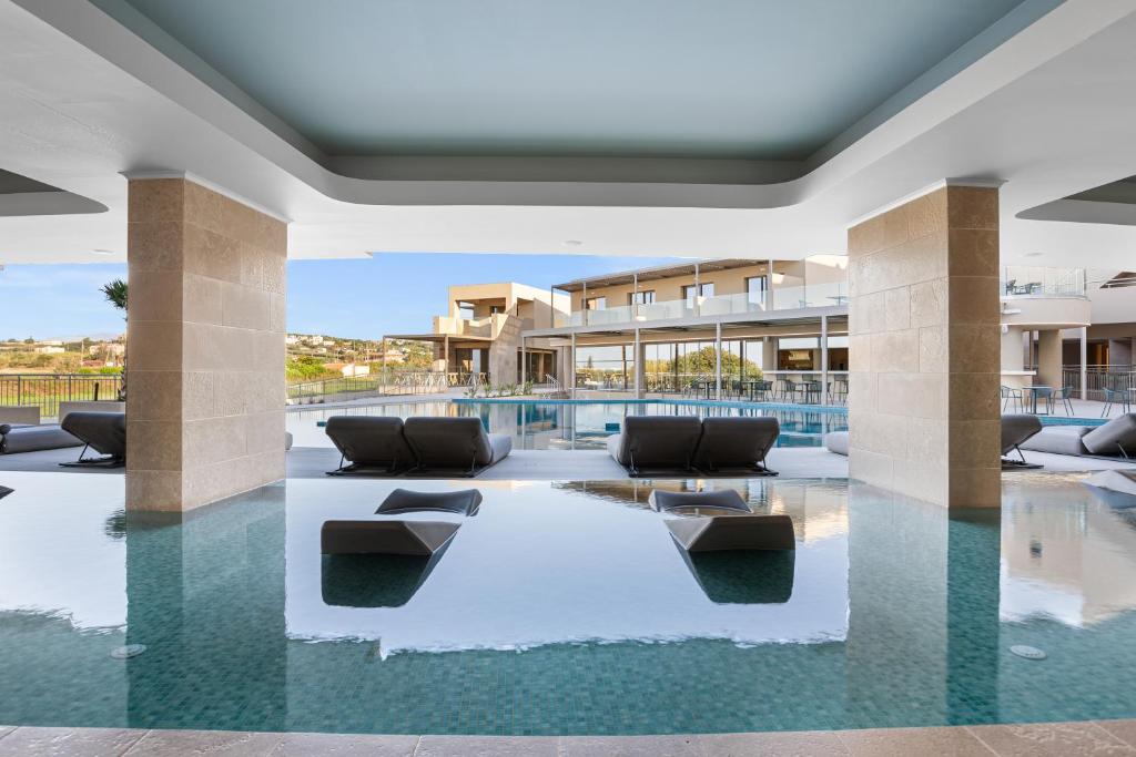 Eleganta atpūtas zona ar baseinu, kurā ir šūpuļkrēsli, kas aicina uz relaksāciju. No terases paveras skats uz apkārtējo ainavu un viesnīcas ēkām.