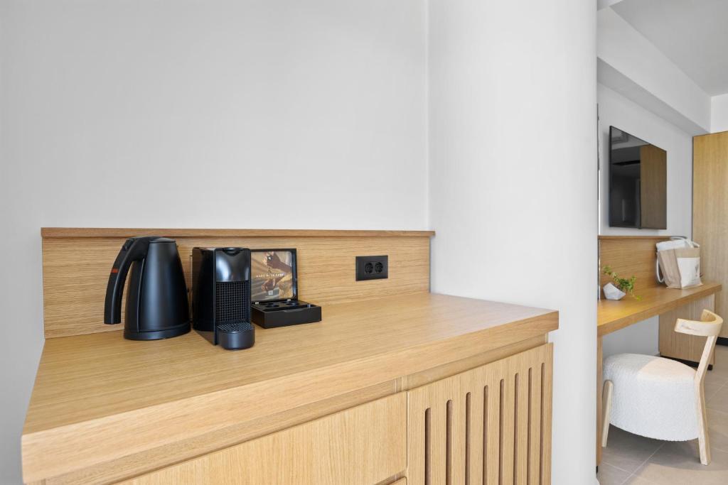 Mūsdienīga viesnīcas istabas stūra ar koka galdu, tējkannu un kafijas automātu, kas nodrošina komfortu un ērtības viesiem. Svaiga un gaiša atmosfēra, kas veicina relaksāciju.